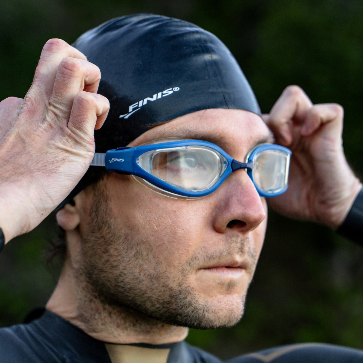 Swimmer adjusting FINIS Alliance Swim Goggles with clear lenses before a swim.
