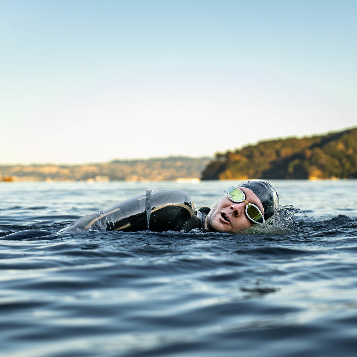 Man swimming in open water wearing FINIS Alliance Goggles with clear lenses.