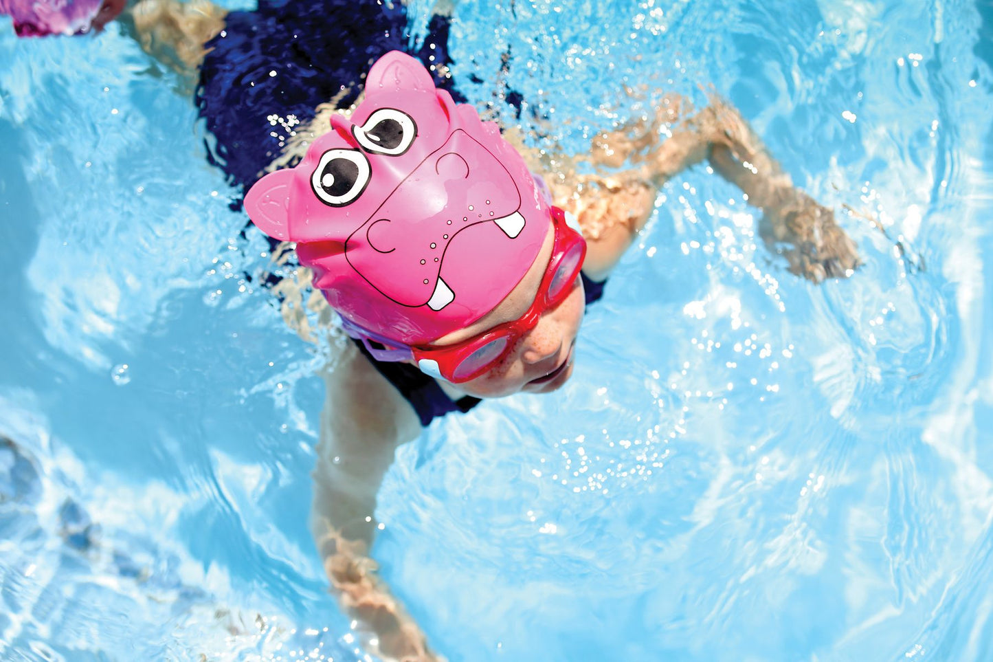 Child swimming with FINIS Animal Heads kids' swim cap in Hippo Pink, action view