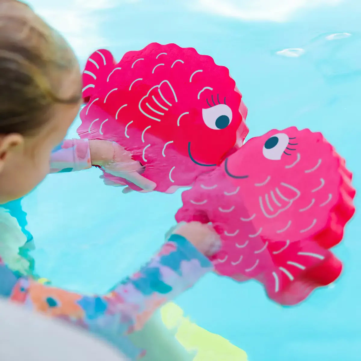 Child using FINIS Floatie Friends pufferfish hand floats during swimming lesson