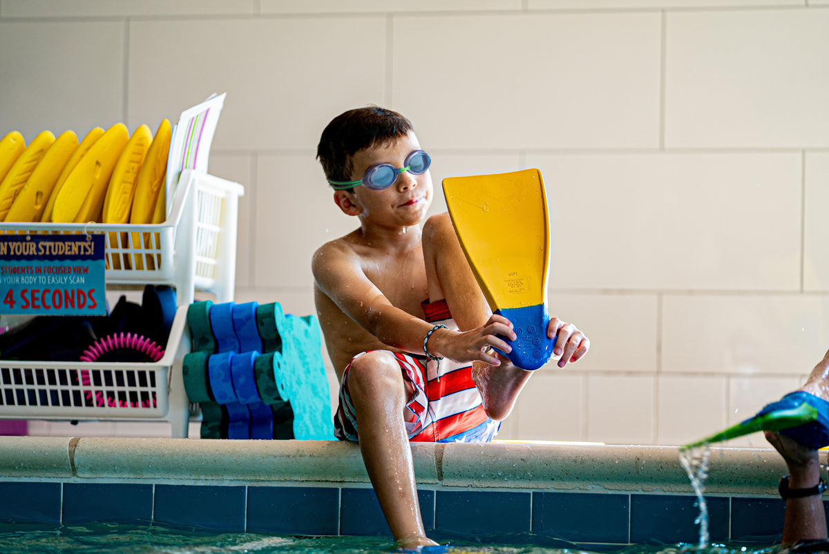 Kids' swim gear including goggles, swim caps, floaties, and fins