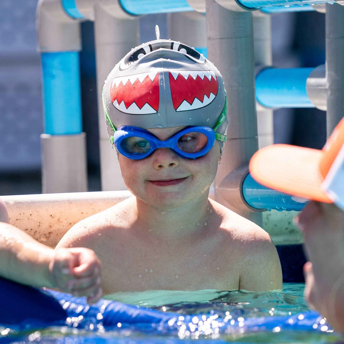 Close-up of child wearing FINIS Fruit Basket Blueberry goggles with shark swim cap