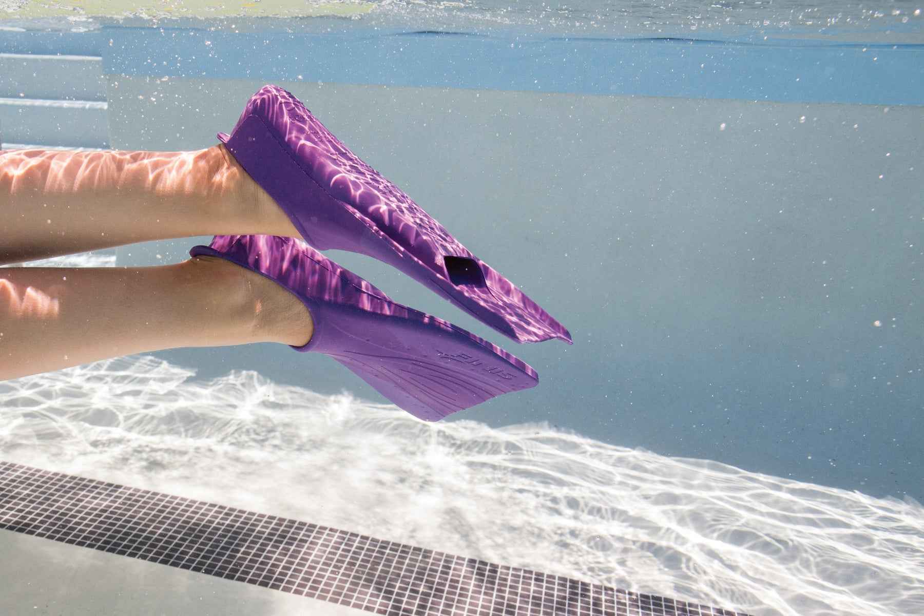 Child holding FINIS Booster Fins Jr 6–8 in Purple by the pool edge
