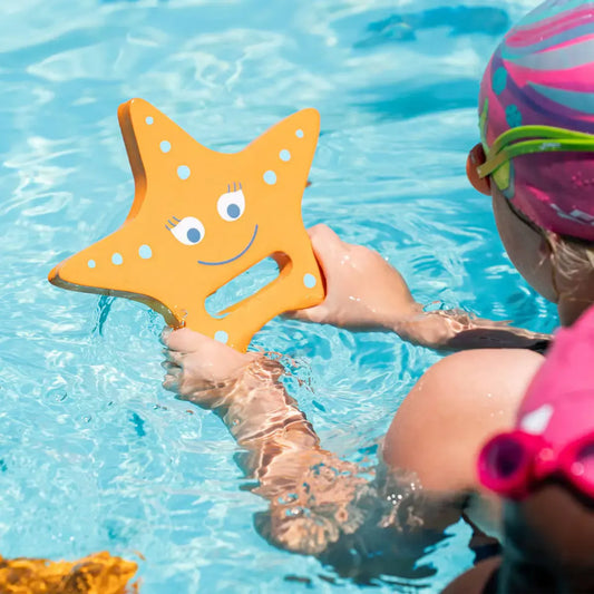 Child holding FINIS Starfish hand float by the pool.