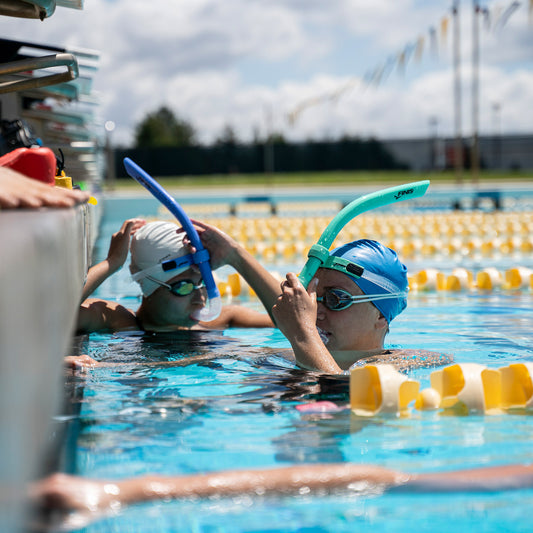Swimmer adjusting FINIS Glide swim snorkel in Mint Green, poolside view