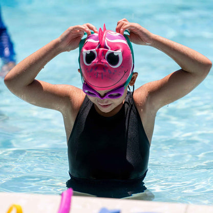 Child with Grape FINIS goggles adjusting a fun fish swim cap at the pool