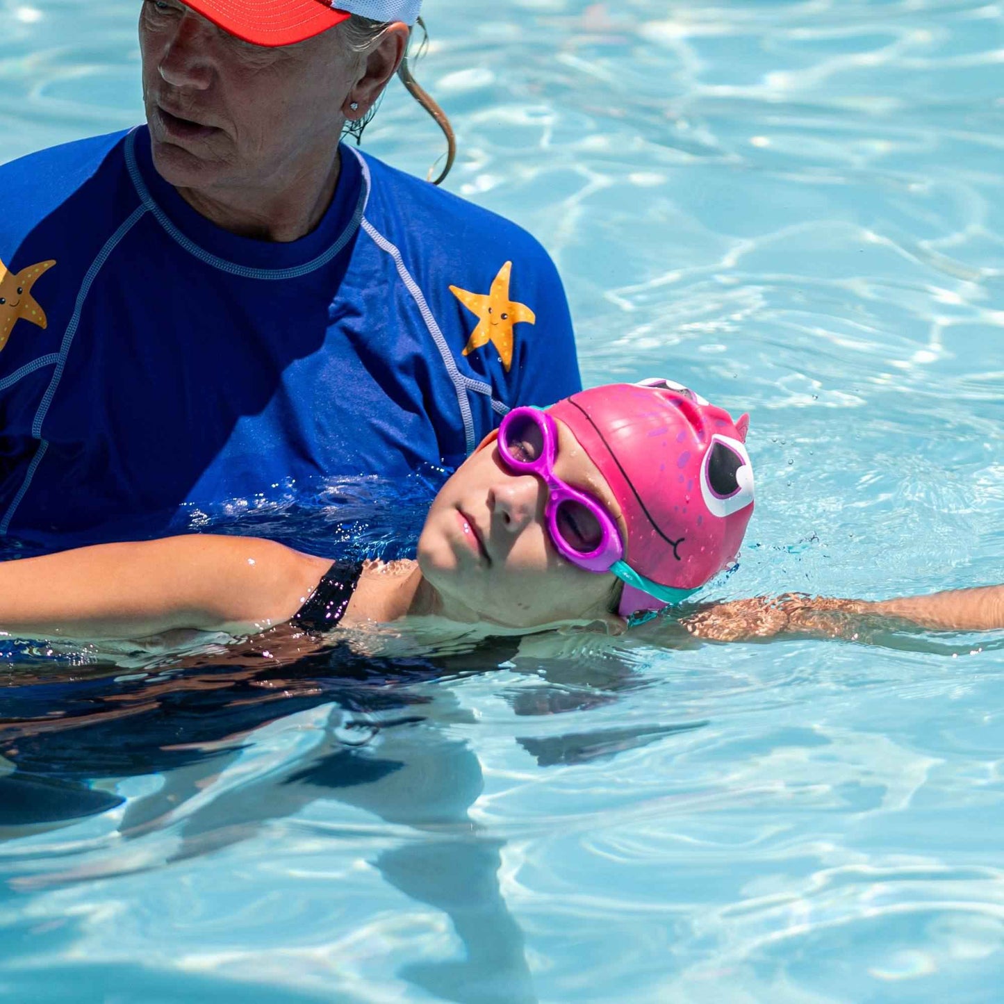 Child wearing FINIS Grape scented swim goggles during swim lesson with instructor