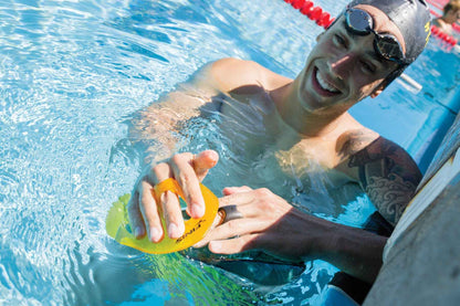 Swimmer using FINIS Iso Paddles Small in black and yellow poolside during technique training