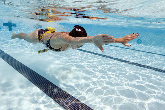 Swimmer using FINIS Tech Toc underwater for hip rotation training in a pool lane