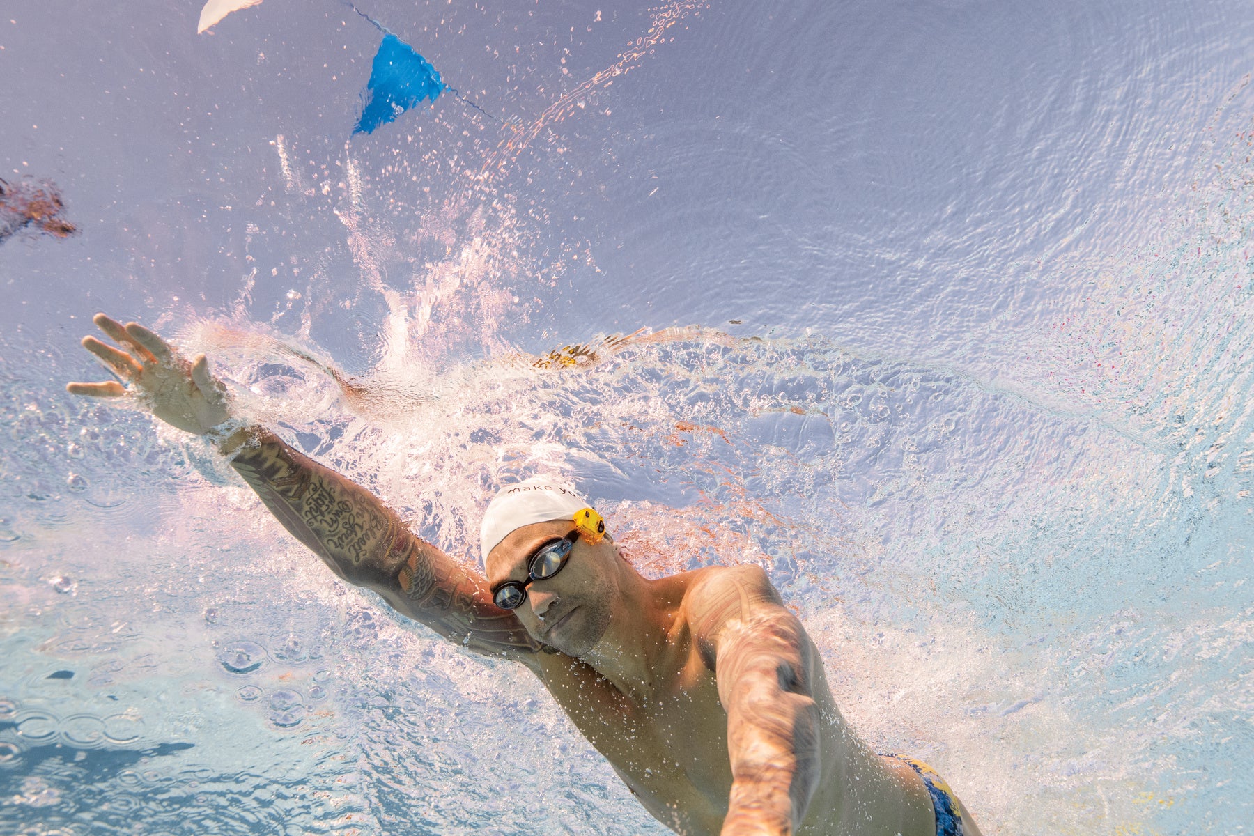 Male swimmer mid-stroke using the FINIS Tempo Trainer Pro during freestyle practice
